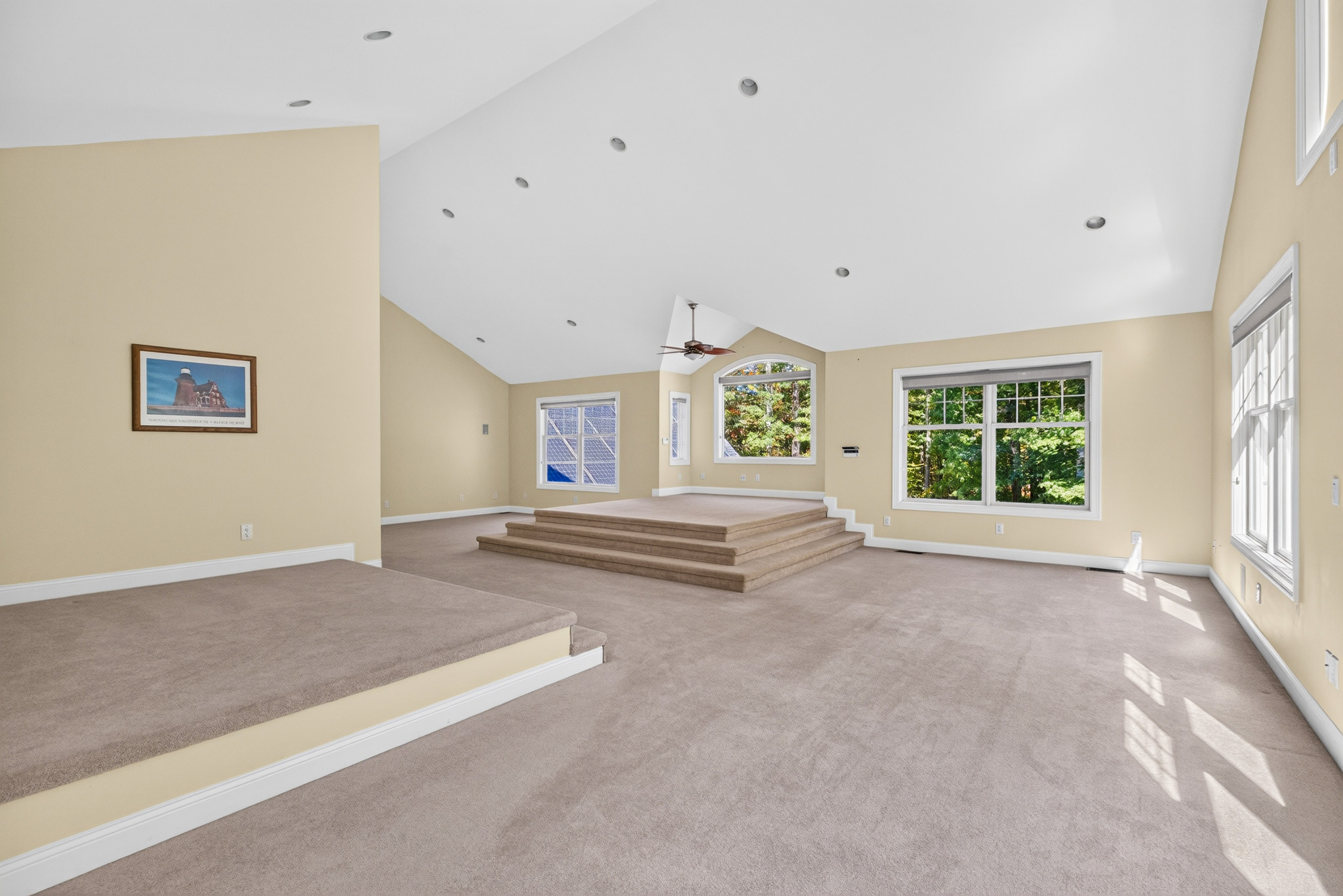 Wide bedroom with vaulted ceiling, raised platform, and woodland views.