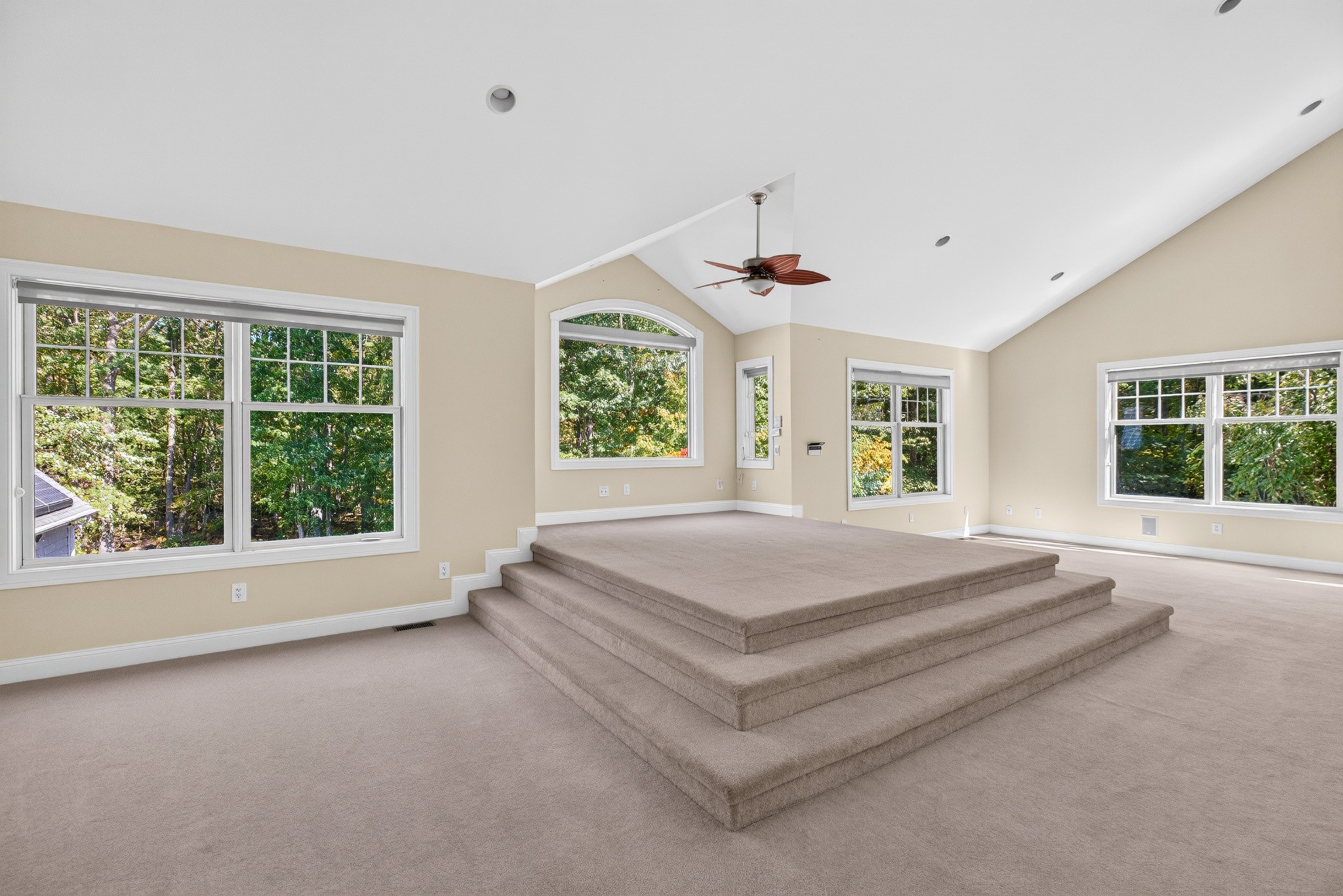 Bright bedroom with a raised platform, vaulted ceiling, and woodland views.