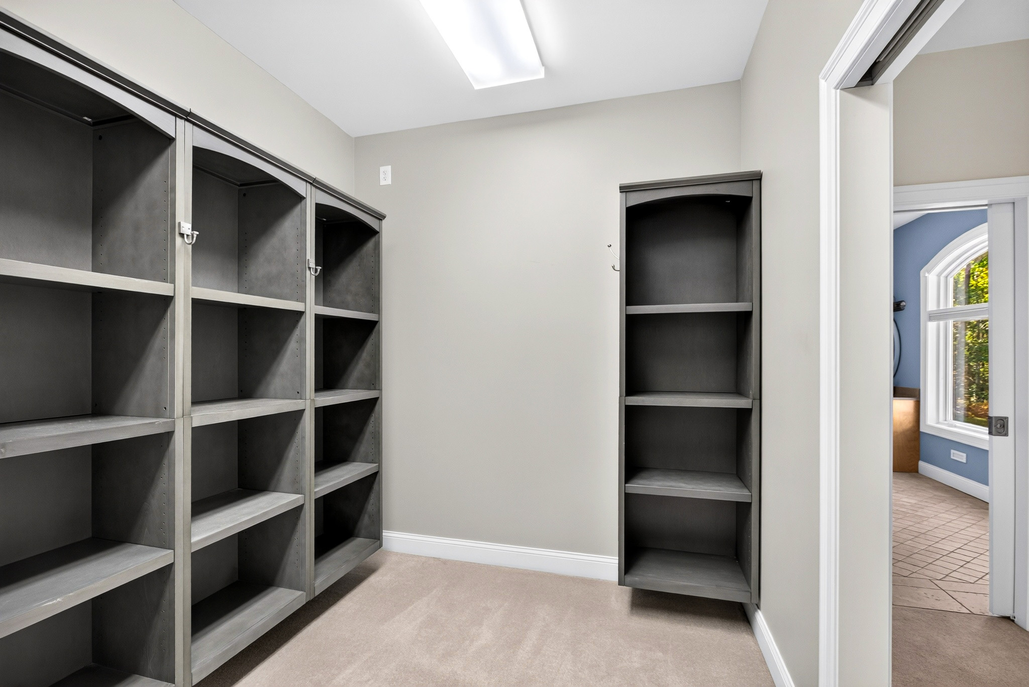 Walk-in dressing room with dark open shelving and a skylight.